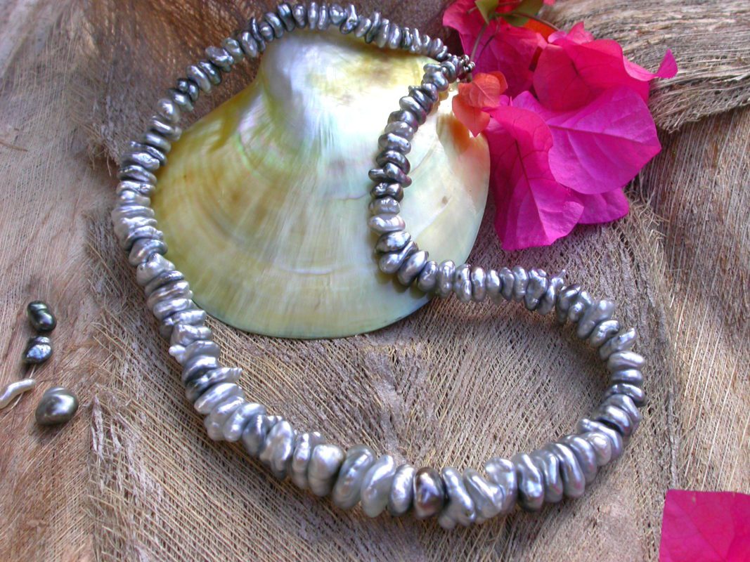 Plusieurs dizaines de Keshis de Tahiti sont réunis pour composer ce splendide collier.Posé sur une coquille de nacre à coté d'une fleur de Bougainvillier.