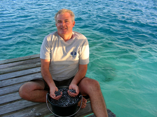 Thierry a le sourire, il pose avec un seau rempli de perle de Tahiti. 
Une récolte plutôt consistante, tout va bien !
