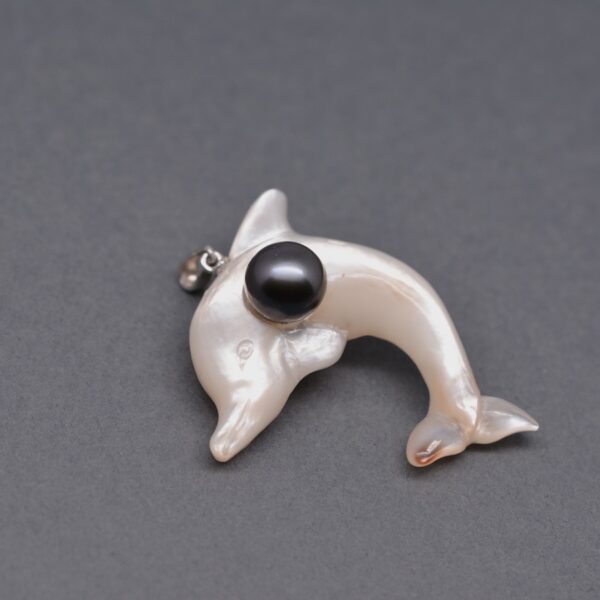 Oua, un splendide dauphin en nacre réalisé par la sculpteuse Christiane de DAWA Création. Un pendentif unique monté avec une véritable perle de Tahiti.