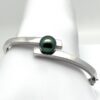 Bracelet Heirima en argent massif 925 avec une perle de Tahiti semi-ronde de 10 mm, couleur verte naturelle, produite sur la ferme perlière de Manihi. Élégant et sécurisé, ce bijou unique est livré comme sur la photo avec certificat d 'origine.