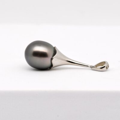 Le pendentif perle APATAKI incarne l’union parfaite entre raffinement contemporain et tradition perlière polynésienne. Monté sur une longue bélière articulée en argent 925 rhodié, ce bijou de 35 mm de hauteur épouse avec grâce les lignes du cou, tout en valorisant une perle d’exception : une perle de Tahiti semi-baroque de 11,7 mm, de qualité A.
