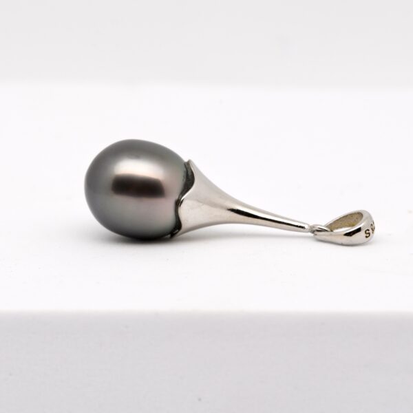 Le pendentif perle APATAKI incarne l’union parfaite entre raffinement contemporain et tradition perlière polynésienne. Monté sur une longue bélière articulée en argent 925 rhodié, ce bijou de 35 mm de hauteur épouse avec grâce les lignes du cou, tout en valorisant une perle d’exception : une perle de Tahiti semi-baroque de 11,7 mm, de qualité A.