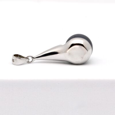 Photographie du pendentif Taenga, suspendu à une chaîne fine. Le bijou présente une monture en argent 925 rhodié de 28 mm, dessinée pour maintenir la perle sans contact direct avec la peau. La perle de Tahiti est ronde, de 10,4 mm, et arbore une teinte bleu azur éclatante, totalement naturelle. Son lustre est intense, sa surface lisse. La lumière met en valeur la forme épurée et contemporaine du pendentif, qui conjugue confort, élégance et durabilité. Ce bijou est présenté sur fond neutre.