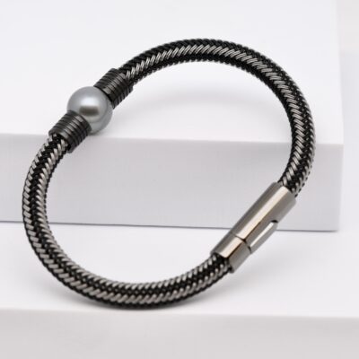 La perle du bracelet Metua est un véritable joyau naturel : ronde parfaite, qualité B, lustre excellent et gris profond aux reflets d’argent. Cette teinte rare et sobre évoque la lumière des lagons à l’aube, lorsque le ciel se mêle à la mer dans un dégradé de gris bleuté. Sa surface lisse et son éclat exceptionnel témoignent du savoir-faire traditionnel polynésien et de la beauté brute de la nature.