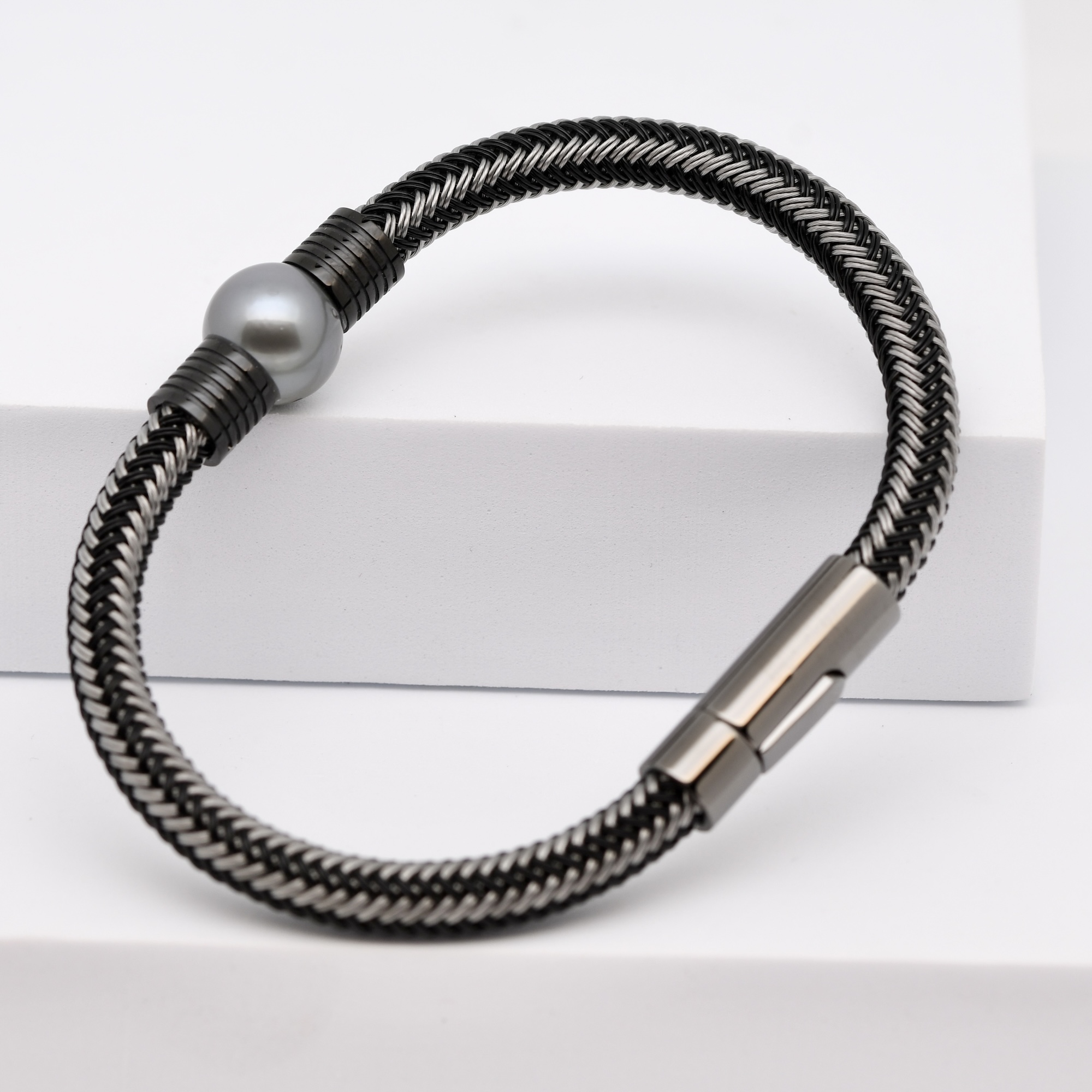 La perle du bracelet Metua est un véritable joyau naturel : ronde parfaite, qualité B, lustre excellent et gris profond aux reflets d’argent. Cette teinte rare et sobre évoque la lumière des lagons à l’aube, lorsque le ciel se mêle à la mer dans un dégradé de gris bleuté. Sa surface lisse et son éclat exceptionnel témoignent du savoir-faire traditionnel polynésien et de la beauté brute de la nature.