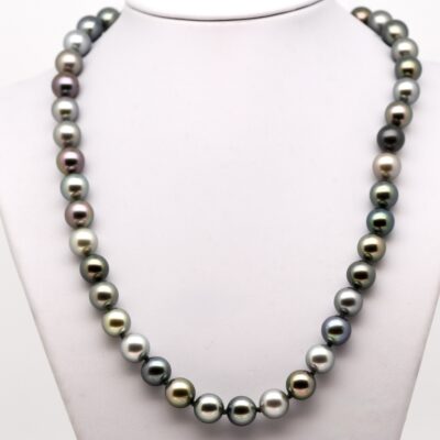 quarante-trois perles de Tahiti rondes aux couleurs naturelles variées, montées avec des nœuds entre chaque perle. Le fermoir bouée en or jaune 18 carats est visible au centre. Les perles présentent un lustre excellent et un dégradé harmonieux de teintes grisées, vertes et bleutées, offrant un rendu élégant et équilibré.