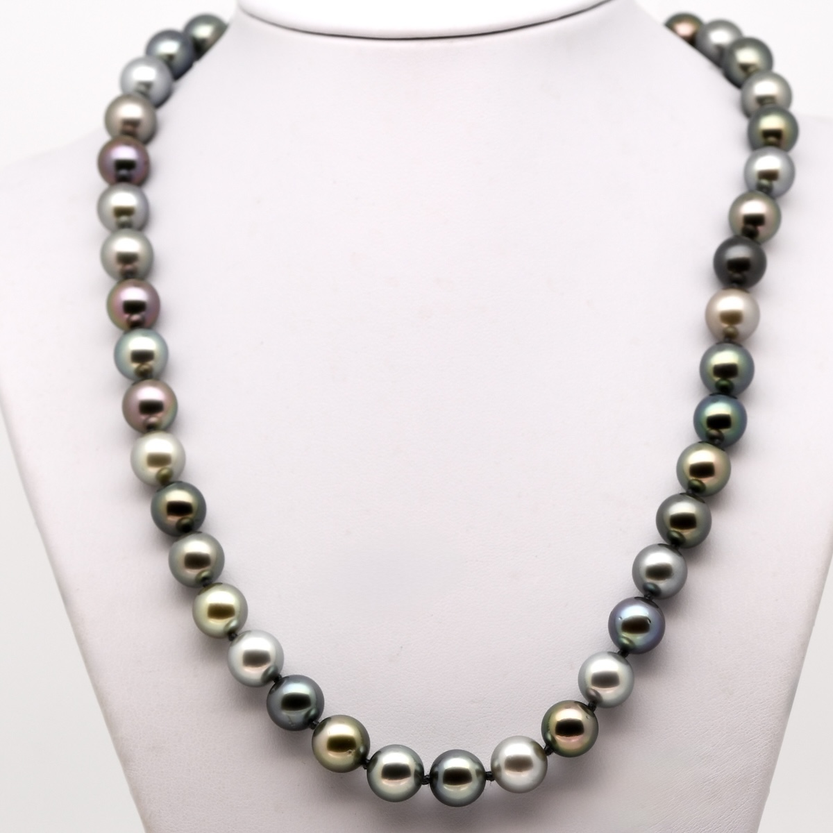 quarante-trois perles de Tahiti rondes aux couleurs naturelles variées, montées avec des nœuds entre chaque perle. Le fermoir bouée en or jaune 18 carats est visible au centre. Les perles présentent un lustre excellent et un dégradé harmonieux de teintes grisées, vertes et bleutées, offrant un rendu élégant et équilibré.