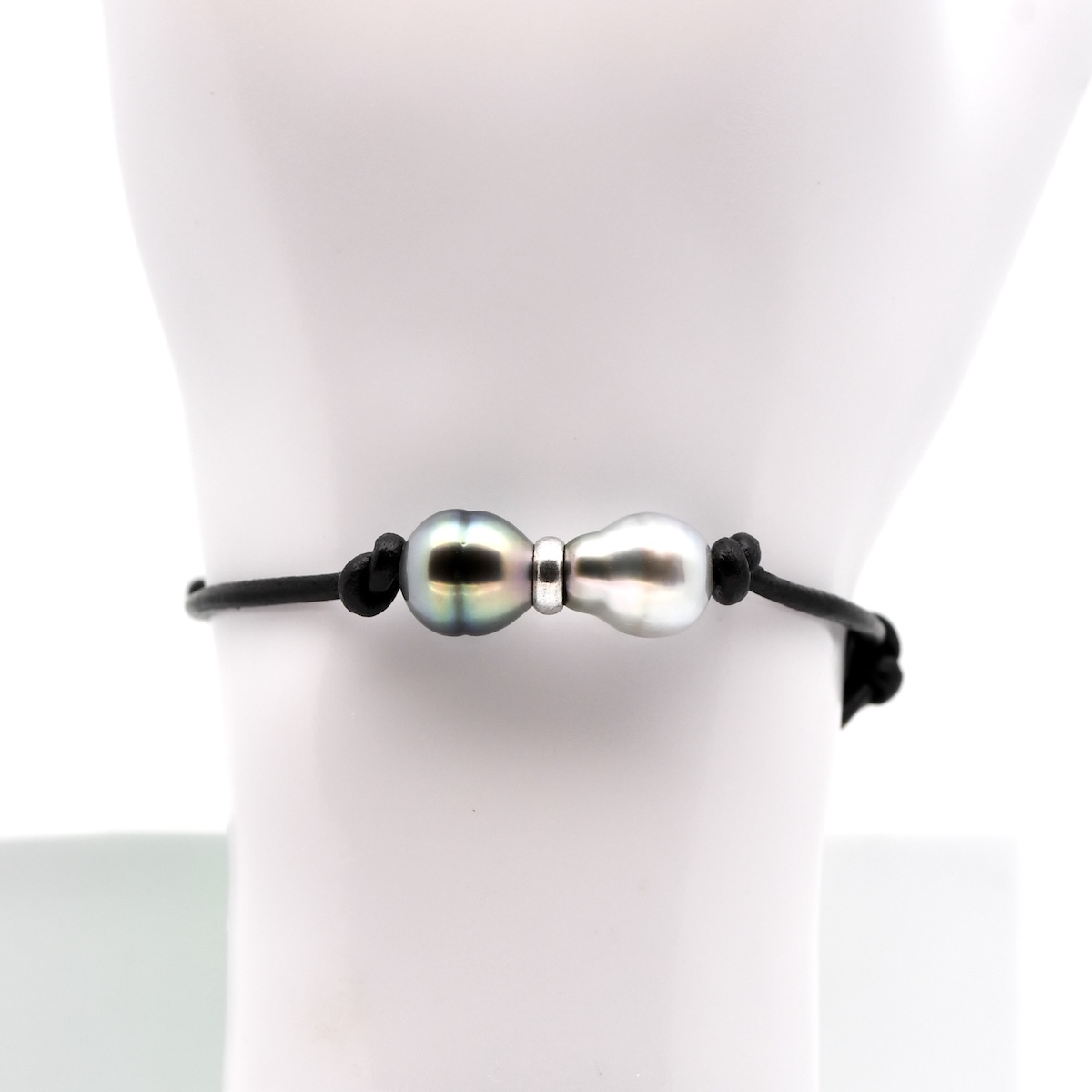 Le bracelet perles Analu est une pièce artisanale qui associe authenticité polynésienne et esthétique contemporaine. Il est composé d’un cuir de vache noir ajustable par nœuds coulissants et orné de deux perles de Tahiti de 9,5 mm, classées qualité A-B selon la classification tahitienne officielle. Ces perles proviennent exclusivement de ma ferme perlière située sur l’atoll de Manihi, dans l’archipel des Tuamotu.