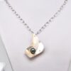 Le pendentif de ce collier est une pièce imposante de 5 × 4 cm, taillée directement dans la coquille d’une huître perlière provenant de la ferme de Manihi. La nacre, d’un blanc lumineux aux reflets irisés, a été sculptée de façon à créer un véritable écrin naturel pour la perle. Au centre du pendentif vient se loger une perle de Tahiti ronde de 9,7 mm, de qualité B, présentant de magnifiques reflets naturels vert profond.