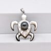 Pendentif Matari en nacre blanche sculptée en forme de tortue avec gravures polynésiennes, perle de Tahiti ronde verte 9,1 mm et bélière en argent rhodié