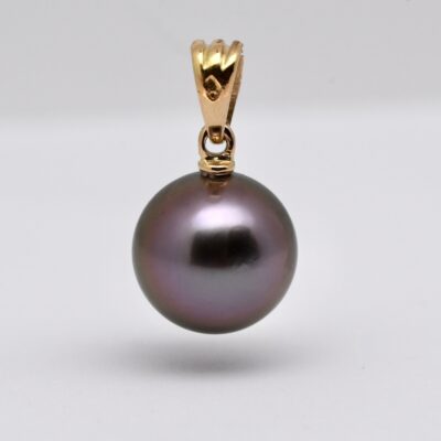 Le pendentif perle Kaloke (Rose en Hawaien) est en or jaune 18 k qui met en lumière une superbe perle de Tahiti ronde de 10,1 mm, sélectionnée pour sa qualité et surtout pour sa couleur violine exceptionnelle, subtilement enrichie de nuances de vert profond. Cette combinaison de teintes naturelles offre un rendu visuel fascinant, oscillant entre reflets pourpres et éclats végétaux, selon l’intensité de la lumière.