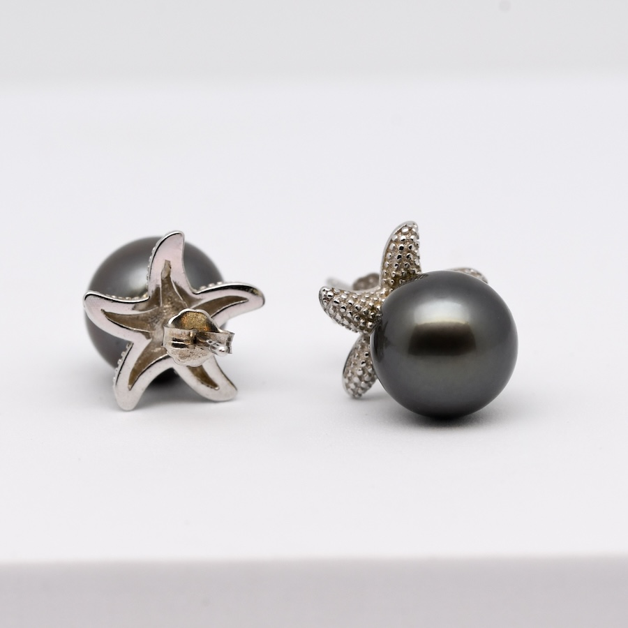 Les boucles d’oreilles perles Hoku sont une invitation directe au voyage au cœur des lagons polynésiens. Leur design original en forme d’étoiles de mer évoque immédiatement les fonds marins cristallins de Manihi, où sont produites les véritables perles de Tahiti qui composent ce bijou.