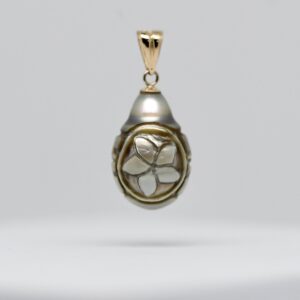 Photographie sur fond blanc du pendentif artisanal EKAHI, composé d'une perle de culture de Tahiti semi-baroque en forme de poire, d'un diamètre de 11,4 mm. La perle présente une couleur naturelle à dominante grise, enrichie de nuances vertes et de reflets dorés. Sa face principale est ornée d'une fleur délicatement sculptée à la main, entourée de motifs tribaux d'inspiration polynésienne. Les reliefs de la sculpture contrastent avec les parties lisses de la nacre. Une élégante bélière articulée en or 9 carats complète cette création originale. La perle provient de la ferme perlière artisanale de Manihi, dans l'archipel des Tuamotu. Le pendentif EKAHI est une pièce unique commercialisée directement par Tahiti Perles Création.